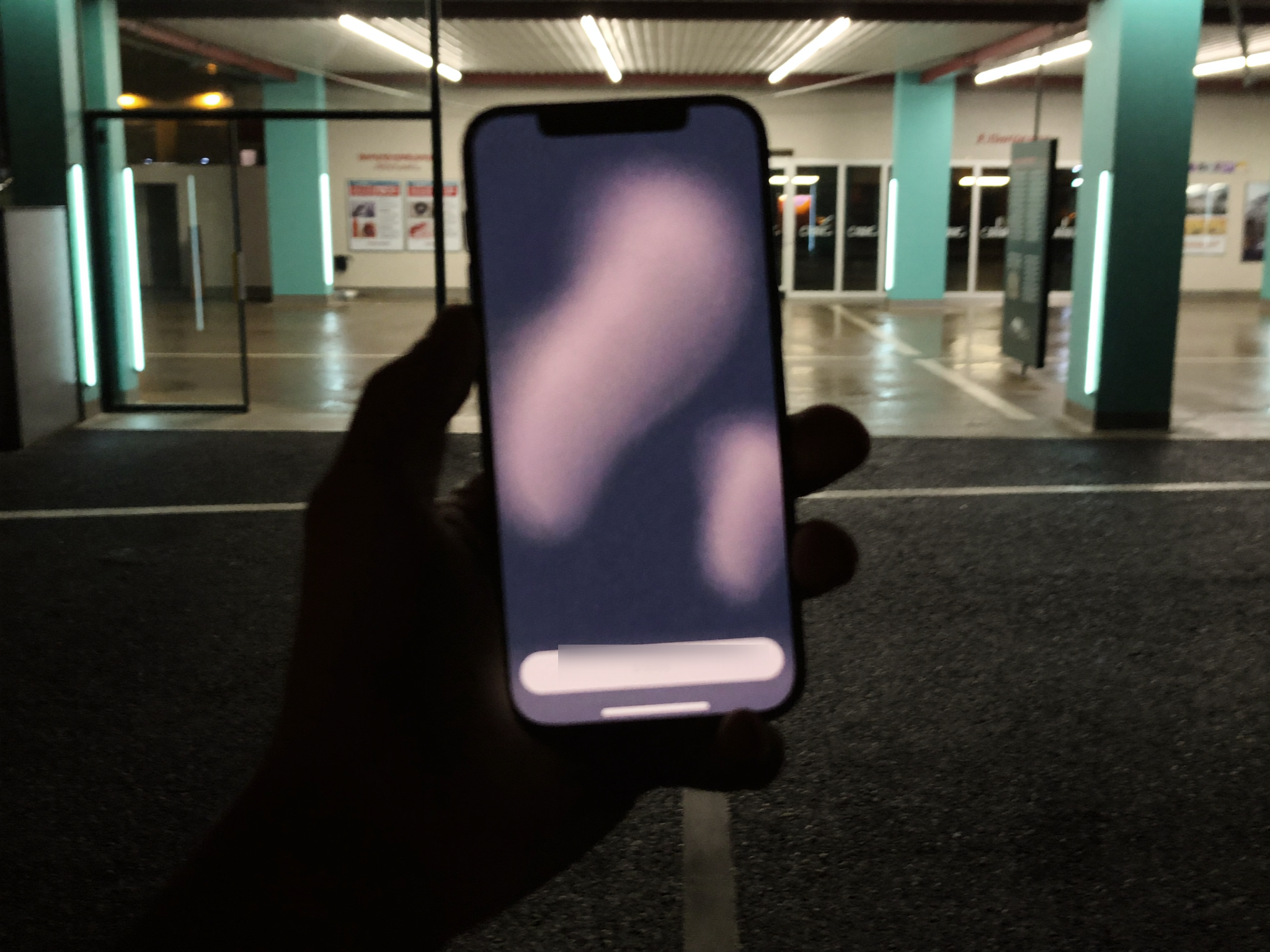 Die WaschCard-App auf dem Smartphone, im Hintergrund die Waschanlage